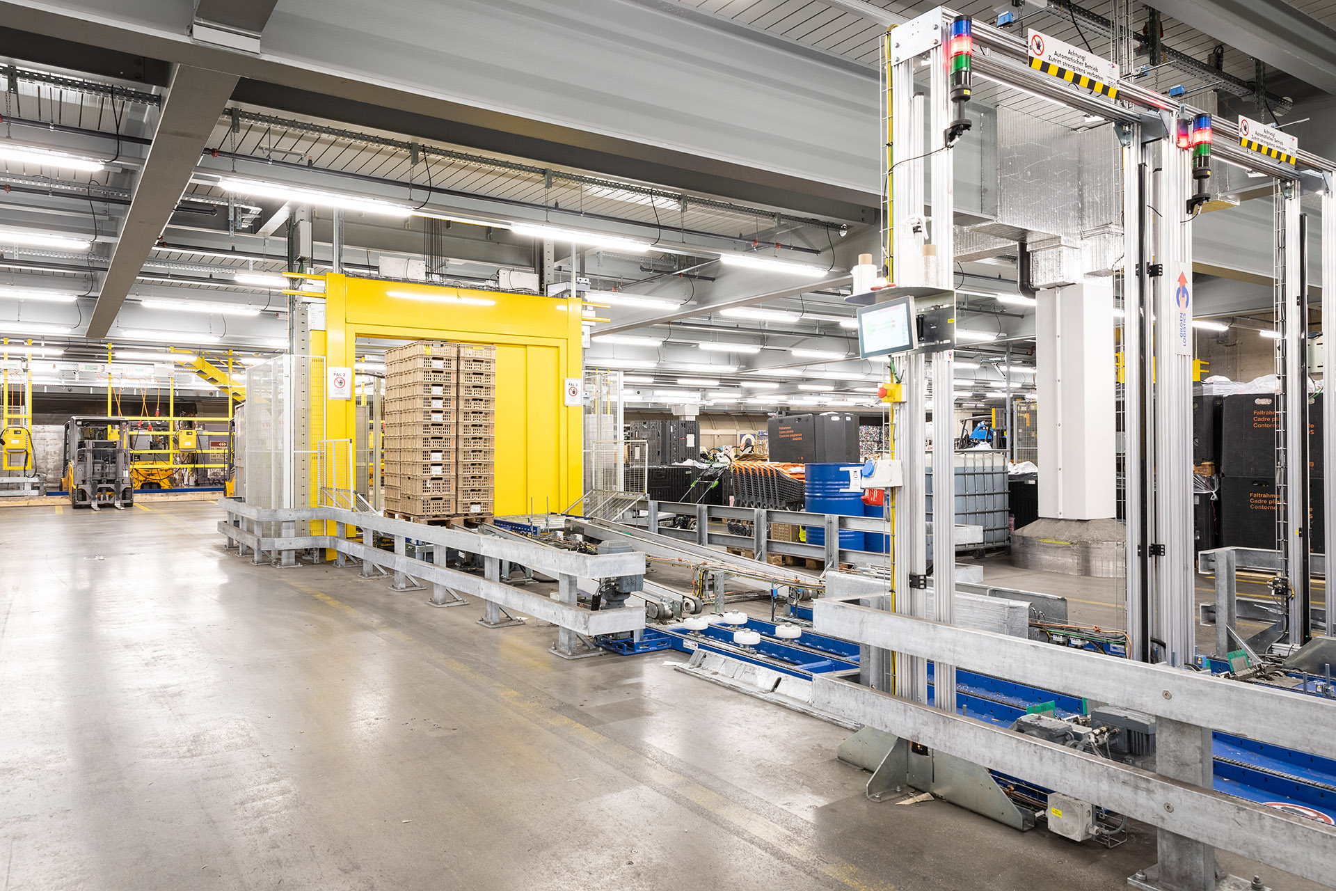 Gebinde mit vorsortierten Altstoffen und Mehrwegkisten werden auf die neue vollautomatische Förderanlage gestellt.